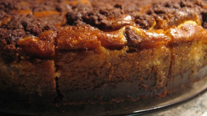 Eine attraktive Kirsch-Schmand-Torte mit Schokostreuseln liegt auf einem Glasplatte, bereit zum Servieren in einer gem&uuml;tlichen K&uuml;che.