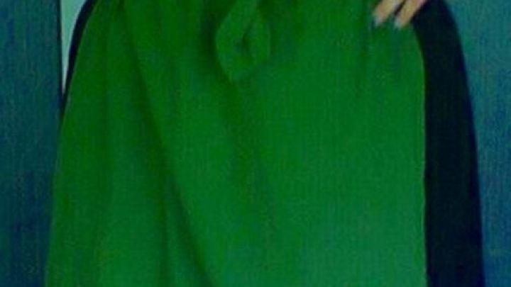 Ein Dirndl mit schwarzem Oberteil und einem knielangen, leuchtend gr&uuml;nen Rock, pr&auml;sentiert stolz eine auf untere H&auml;lfte.