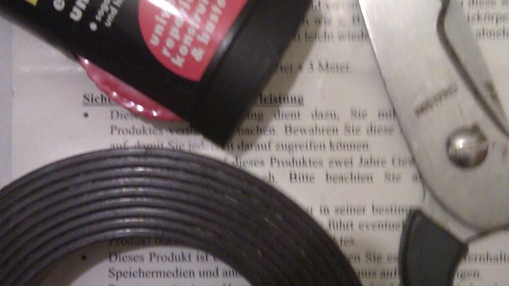 Kleines Magnetband liegt neben einer Schere und einem Kleber auf einem Blatt Papier mit Anleitung, um Notizzettel zu befestigen.