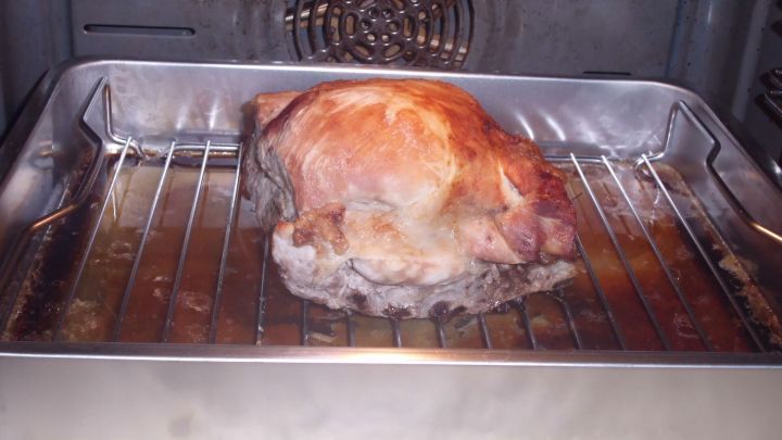 Ein saftiger Ostpreu&szlig;ischer Rippenbraten br&auml;t im Ofen auf einem Rost, umgeben von einer gl&auml;nzenden Bratfl&auml;che.