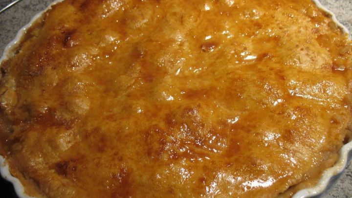 Ein goldbrauner, frisch gebackener Apfelkuchen k&uuml;hlt auf einer grauen Arbeitsfl&auml;che ab.