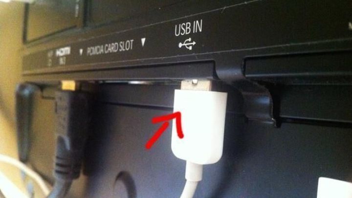 Ein USB-Ladeger&auml;t ist mit einem TV-Ger&auml;t verbunden, um ein Handy aufzuladen, w&auml;hrend es im Wohnzimmer steht.