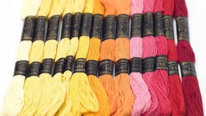 Bunte Stickgarne sind nach Farben und Nummern ordentlich in einer Reihe angeordnet, um die Auswahl zu erleichtern.