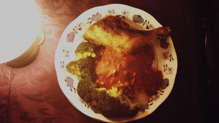 Ein gebratenes St&uuml;ck afrikanisches H&auml;hnchen liegt auf einem Teller mit Gem&uuml;se und Sauce, umgeben von sanftem Licht.