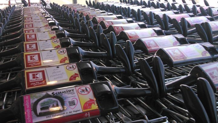 Einkaufswagen stehen geordnet in Reihen; Werbung zeigt "Kaufland", "Schmidt", mit Hinweisen und Logos.