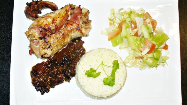 Eine Putenrolle liegt auf einem wei&szlig;en Teller, umgeben von Reis, Gem&uuml;se und einer dunklen Sauce in einem ansprechenden Arrangement.