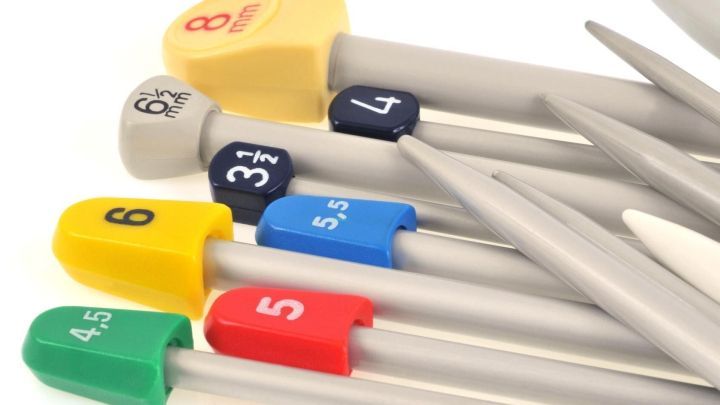 Eine Reihe von Stricknadeln in verschiedenen Farben und Gr&ouml;&szlig;en, die ordentlich nebeneinander angeordnet sind, zeigt Nadelst&auml;rken.