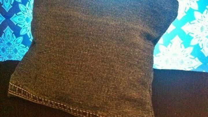 Eine Kosmetiktasche aus alter Jeans liegt auf einem schwarzen Untergrund, umgeben von einem bunten, leuchtenden Hintergrund.