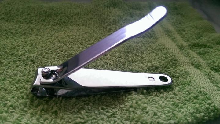 Ein gl&auml;nzender Nagelklipser liegt auf einem gr&uuml;nen Tuch, bereit, um Fingern&auml;gel zu k&uuml;rzen.