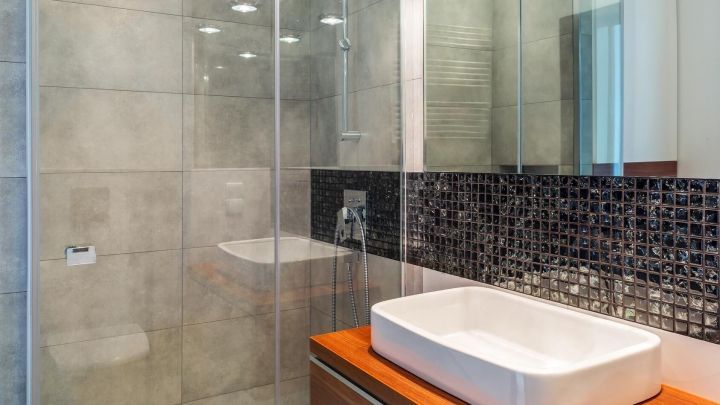 Ein modernes Badezimmer mit einer Glasduscht&uuml;r, die in einem eleganten Ambiente steht, ideal zum Entfernen von Kalk.