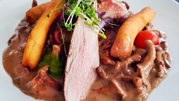 Saftig zubereitetes Fleisch liegt auf einer cremigen Sauce, umgeben von Gem&uuml;se und Garnierung, perfekt f&uuml;r Sous vide.