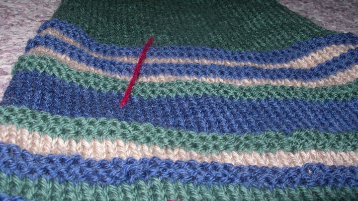 Ein gestreiftes Strickst&uuml;ck liegt flach auf einem grauen Untergrund, mit roten Markierungen f&uuml;r den psychologischen Trick.