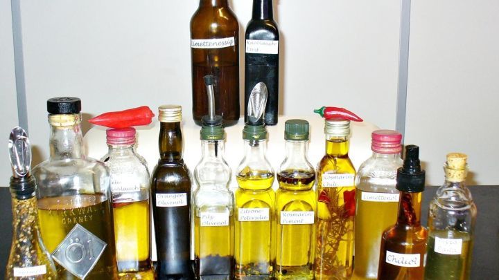 Eine Reihe von verschiedenen Kr&auml;uter&ouml;len und Kr&auml;uteressigen steht auf einem Tisch, bereit zur Verwendung in der K&uuml;che.