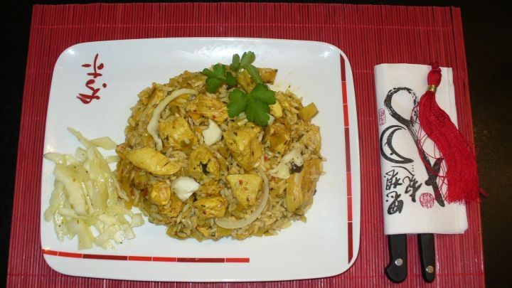 Ein Teller mit Wei&szlig;kohl-H&auml;hnchenbrust und Kimchi liegt auf einem roten Platz, garniert mit Koriander und Seitensalat.