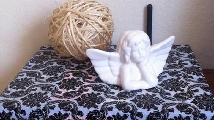 Ein Router ist auf einem h&uuml;bschen Buch versteckt, umgeben von einer dekorativen Kugel und einer Engelsfigur.