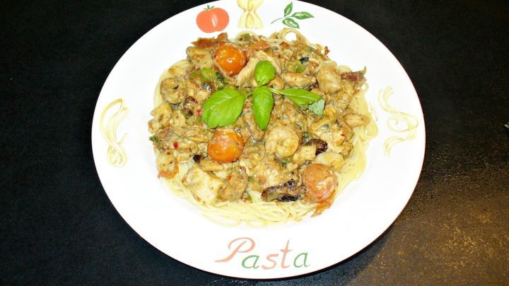 Eine Sch&uuml;ssel mit Neptun-Pfanne, die Fisch und Meeresfr&uuml;chte enth&auml;lt, liegt auf einem Tisch und wird von frischen Kr&auml;utern dekoriert.