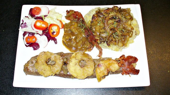 So wird Leber im Backofen richtig zart: Mit Apfelscheiben, Zwiebeln und knusprigem Speck wie auf diesem Teller gelingt sie dir perfekt.