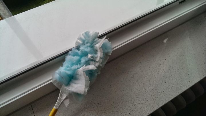 Ein Reinigungstuch mit blauen Fransen liegt auf einem Fensterrahmen. Es wird genutzt, um die schwierigen Rillen zu putzen.