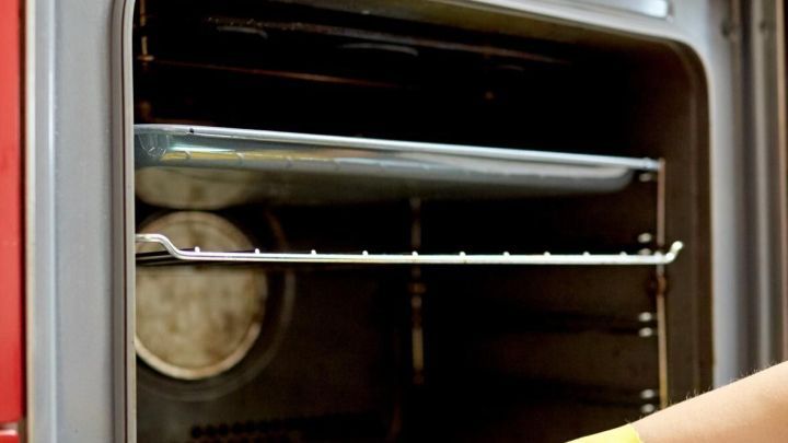 Ein gl&auml;nzender Backofen wird mit einem Schwamm und gelben Handschuhen gereinigt, um ihn sauber und gepflegt zu halten.