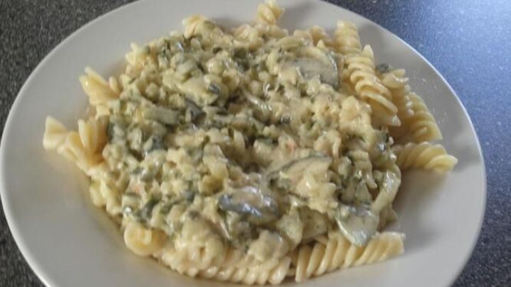 Ein Teller Nudeln ist mit einer cremigen Gurkenso&szlig;e bedeckt und auf einer dunklen Arbeitsplatte platziert.