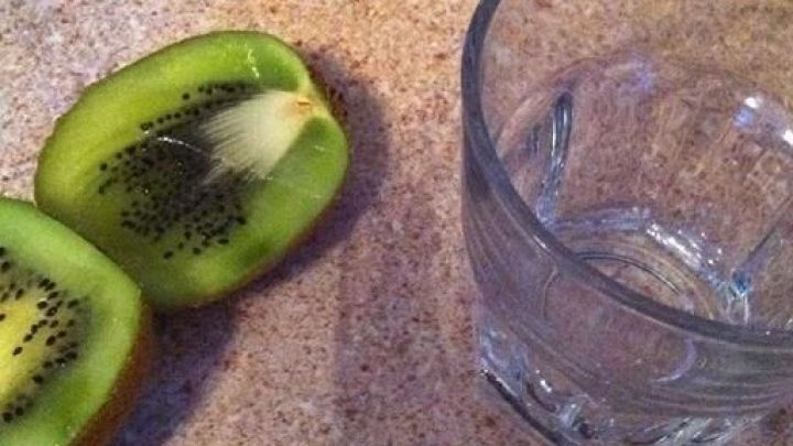Eine halbierte Kiwi liegt neben einem Glas auf einer Arbeitsfl&auml;che, bereit f&uuml;r eine einfache Schalenentfernung.