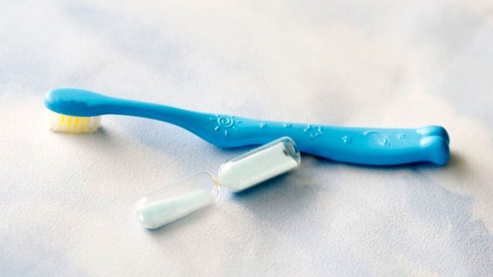 Eine blaue Zahnb&uuml;rste liegt auf einem hellen Untergrund, daneben eine ge&ouml;ffnete Tube Zahnpasta, bereit zum Z&auml;hneputzen.