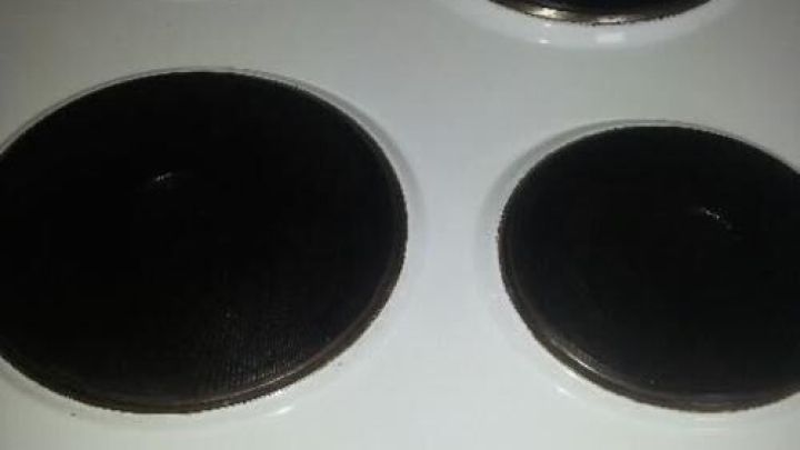 Eine alte Herdplatte liegt auf einer weißen Oberfläche, während der Benutzer beginnt, sie zu reinigen, um sie ansehnlich zu machen.