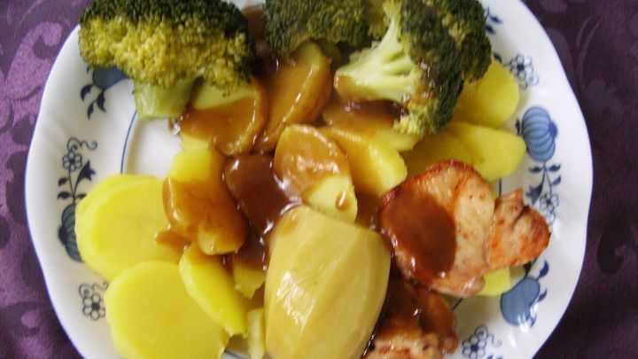 Auf einem Teller liegen Safrankartoffeln, Brokkoli und H&uuml;hnerbrustfilets, die in einer Sauce angerichtet sind.