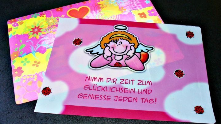 Bunte Platzsets mit einem Engel und dem Spruch &bdquo;Nimm dir Zeit zum Gl&uuml;cklichsein und genie&szlig;e jeden Tag&ldquo; zur Weiterverwendung.