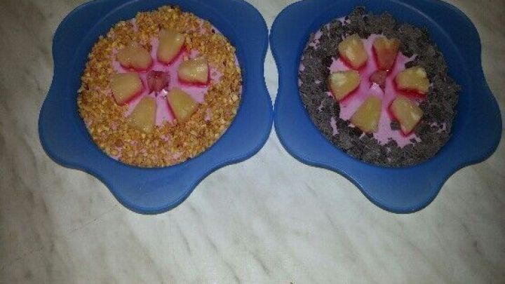 Zwei blaue Schalen enthalten fruchtiges Quark-Buttermilch Dessert, dekoriert mit Erdbeeren und buntem Topping.