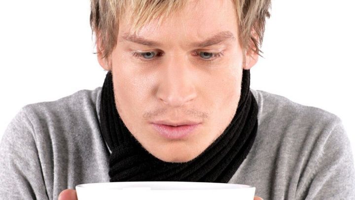 Ein Mann in einem grauen Pullover und Schal h&auml;lt eine wei&szlig;e Sch&uuml;ssel in den H&auml;nden und sieht nachdenklich hinein.