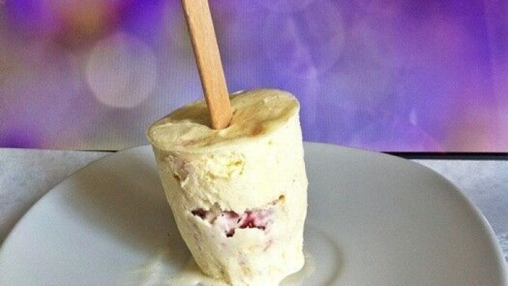 Ein cremiges Vanilleeis mit Erdbeerkern steht auf einem wei&szlig;en Teller, umgeben von einer eleganten, lila Hintergrunddekoration.