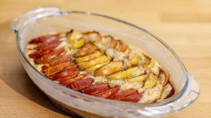 Ein Auflauf mit warmen, s&uuml;&szlig;en Apfelspatzen ist goldbraun gebacken und steht auf einem Holzuntergrund.