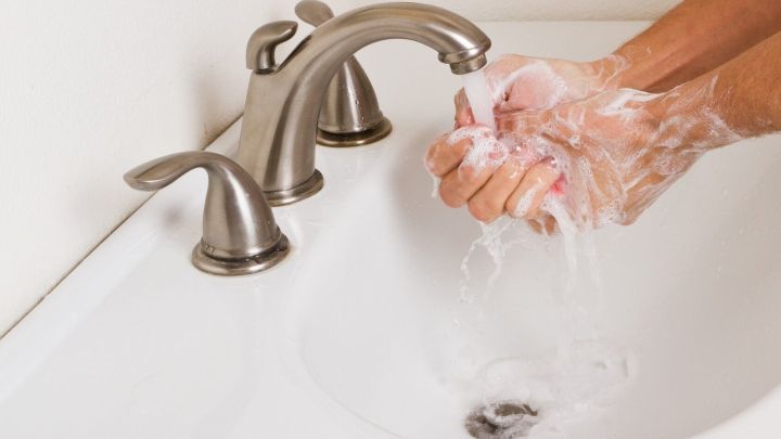 H&auml;nde werden mit Seife gewaschen, w&auml;hrend Wasser aus einem modernen Waschbecken flie&szlig;t, um Hygiene zu f&ouml;rdern.