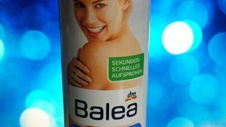 Ein Spray-On Bodylotion von Balea steht vor einem blauen, glitzernden Hintergrund und zeigt eine lachende Frau.