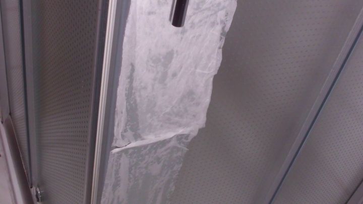 Kalkablagerungen befinden sich an einer Duschwand, w&auml;hrend der Raum sauber und ausgestattet mit Fliesen ist.