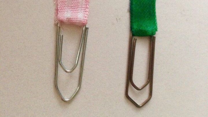 B&uuml;roklammern dienen als Lesezeichen, w&auml;hrend sie auf einem hellen Hintergrund pr&auml;sent sind. Pinke und gr&uuml;ne Lesezeichen aus B&uuml;roklammern heben sich deutlich hervor.