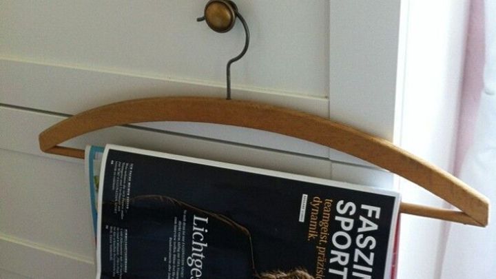 Ein Kleiderb&uuml;gel h&auml;lt eine Zeitung, die an einem Schrank h&auml;ngt, w&auml;hrend der Raum hell und freundlich wirkt.