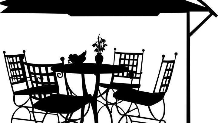 Ein Sonnenschirm steht &uuml;ber einem Tisch mit vier St&uuml;hlen, umgeben von einer einladenden Gartenatmosph&auml;re.