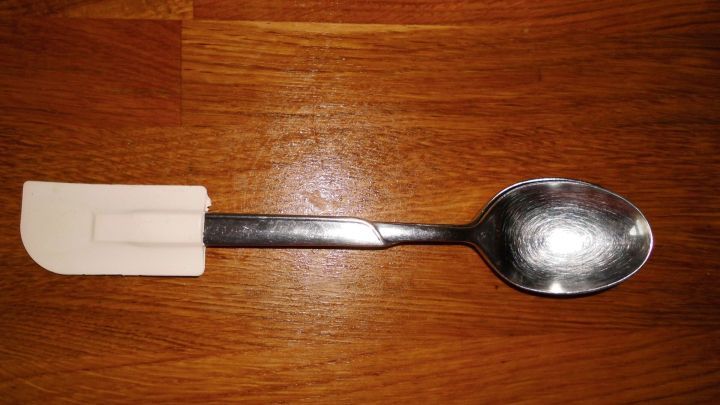 Ein Teigschaber mit variablem Griff liegt auf einer Holzoberfl&auml;che, bereit zum Mischen und Formen von Teig.