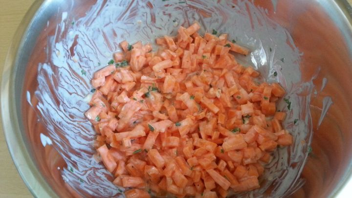 Geriebene M&ouml;hren liegen in einer Sch&uuml;ssel, vermischt mit Naturjoghurt, in einer hellen, heimischen K&uuml;che.