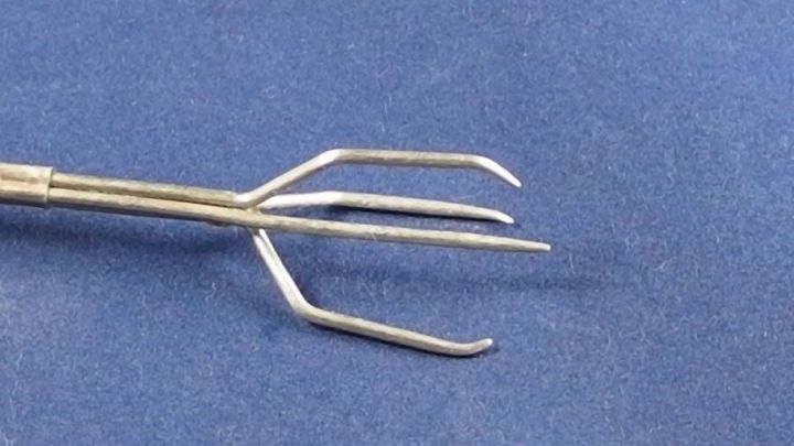 Eine dreizinkige Gabel liegt auf blauem Hintergrund; sie wird verwendet, um Pellkartoffeln zu pellen.