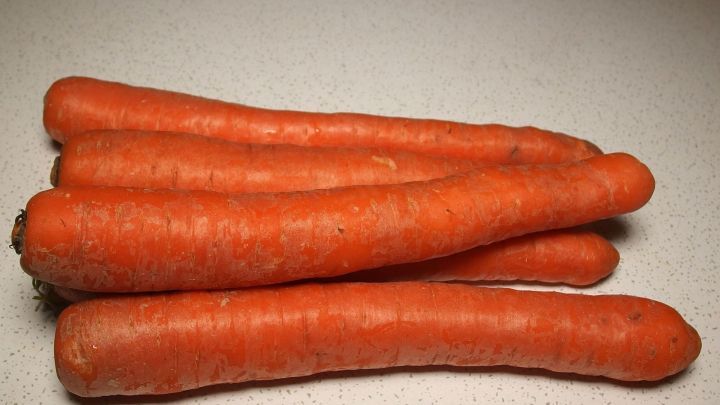 Frische, orangefarbene Karotten liegen auf einer hellen Oberfl&auml;che und deuten auf ihre Nutzung zur F&ouml;rderung einer nat&uuml;rlichen Br&auml;une hin.