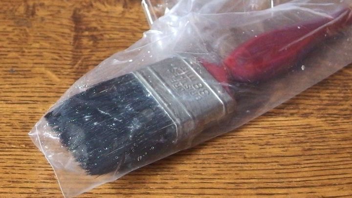 Ein Pinsel eingewickelt in Frischhaltefolie liegt auf einer Holzoberfl&auml;che, um das Austrocknen zu verhindern.