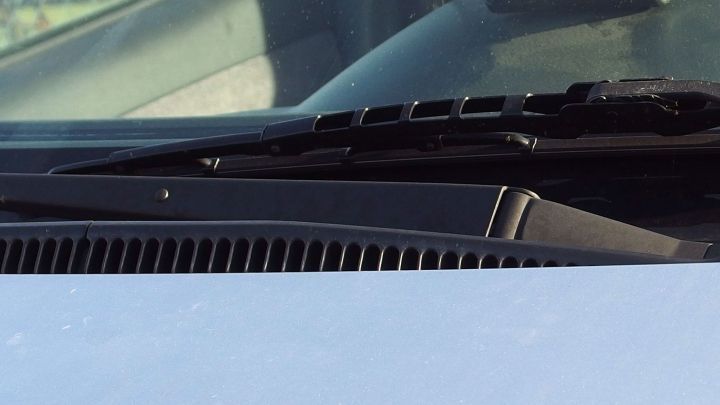 Ein Scheibenwischer bewegt sich &uuml;ber die B-Seite einer Windschutzscheibe in einem Fahrzeug, w&auml;hrend die Sonne scheint.