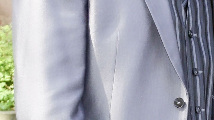 Ein eleganter Anzug wird pr&auml;sentiert, w&auml;hrend die Person vor einem Hintergrund aus Pflanzen steht und sich auf ein Gespr&auml;ch vorbereitet.