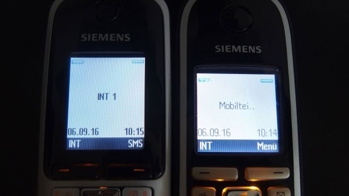 Zwei Siemens-Festnetztelefone mit leuchtenden Bildschirmen zeigen Anrufinformationen im Gespr&auml;chsmodus.