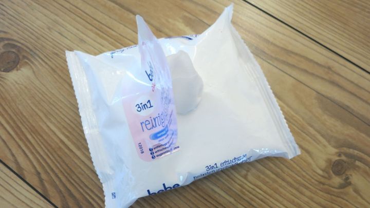 Eine Packung bebe Reinigungst&uuml;cher liegt auf einem Holztisch; die Verpackung ist ge&ouml;ffnet und die T&uuml;cher sind sichtbar. Text: &bdquo;3in1 reinigend&ldquo;.