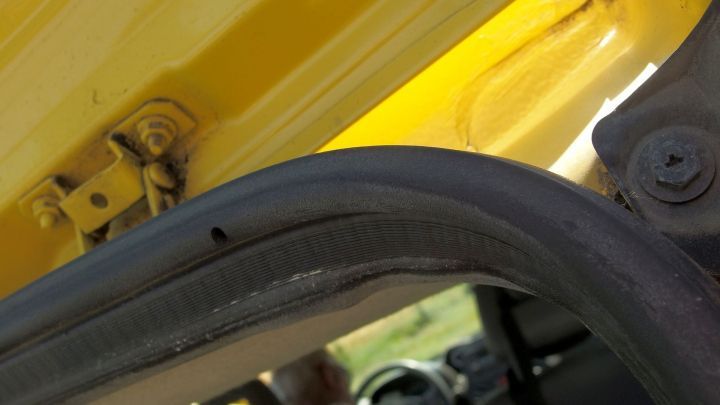 Eine Gummidichtung wird an einer ge&ouml;ffneten Autot&uuml;r auf Vordermann gebracht. Der Innenraum des Fahrzeugs ist im Hintergrund.