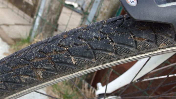 Ein Fahrradreifen mit sichtbaren Abnutzungserscheinungen liegt auf dem Boden, w&auml;hrend die Umgebung verschwommen ist.